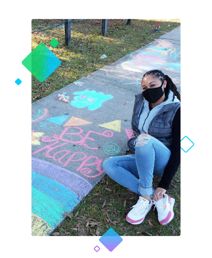 adolescent sitting by a sidewalk decorated with chalk